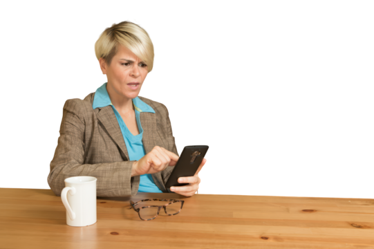 A woman is sitting at a table with a cell phone in her hand