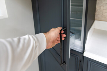 A man opens the door of a built-in refrigerator