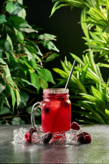 Refreshing raspberry lemonade in a glass jar with ice on a dark background