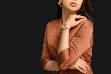 Elegant young woman with wristwatch on black background, closeup