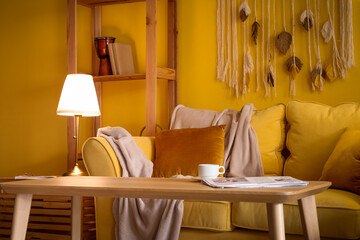 Interior of stylish living room with cozy yellow sofa and glowing lamp