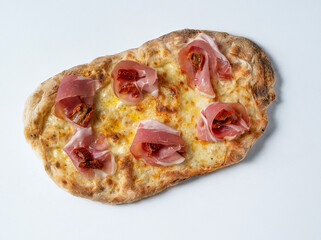 A delicious freshly baked artisanal pinsa romana, garnished with slices of ham and sun-dried...