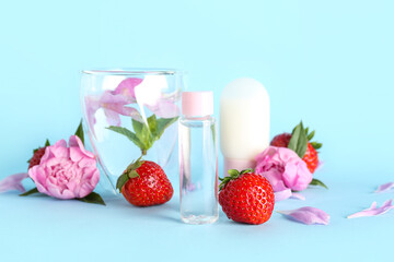 Composition with cosmetic products, glass of water, strawberry and peony flowers on color background