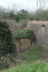 View of massive brick walls and defensive structures of Petrovaradin Fortress, Novi Sad, Serbia. Overgrown architecture blending history and nature in a peaceful, forgotten corner of the fort.