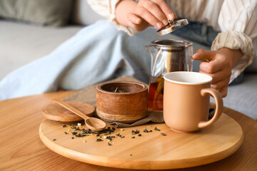 Young woman brewing tea at home, closeup
