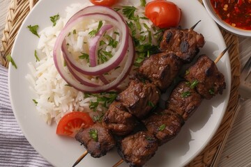 Overhead view of meat kebab on a plate with rice and onion