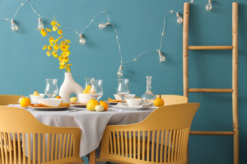 Autumn table setting with pumpkins and yellow flowers in festive room