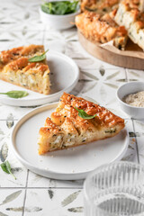 Greek pie spanakopita with feta cheese and spinach on a white plate on printed tile background