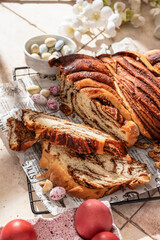 Easter baking. Homemade Easter Chocolate babka or brioche bread cutted with easter eggs and flowers in bright sunlight. Sweet yeast dough with chocolate filling
