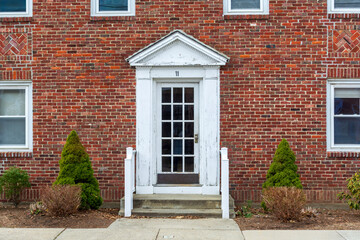 Aged French door with white pediment in Brighton, Massachusetts, USA
