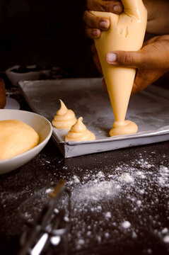 Pastry chef using a pastry bag with freshly prepared cream for making sweets.
