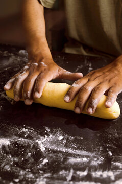 Floured hands work the dough on a dark table, evoking the dedication and artistry of artisanal baking.