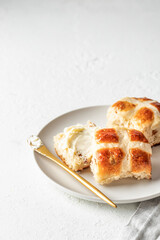 Traditional Easter hot cross buns on white plate with butter on white background with text space. Delicious Easter breakfast