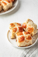 Traditional Easter hot cross buns on white plate on white background. Delicious Easter breakfast