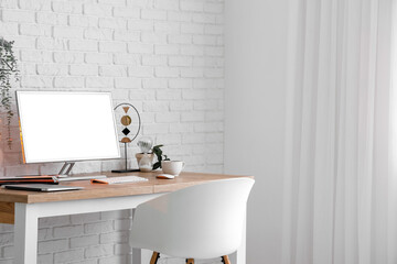 Stylish workplace with modern computer near light brick wall