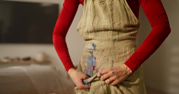 Close up of an artist wiping his fingers in multi-colored paint on his front ones in the studio