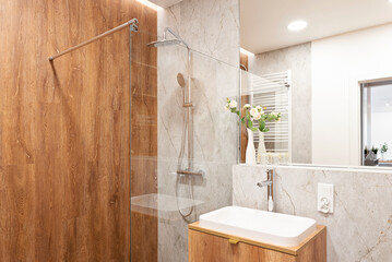  Modern bathroom with ceramic sink on wooden cabinet, mirror, stylish toilet, marble tile on the...