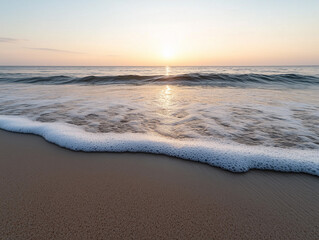Sunrise over the calm ocean waves at a sandy beach with gentle foam on the shore