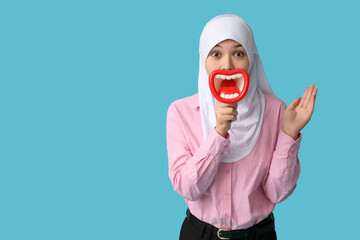 Young Asian Muslim woman with funny megaphone on blue background. National Be Heard Day