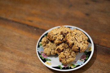 cookies, oatmeal cookies resting over a little dish plate, on a wooden table