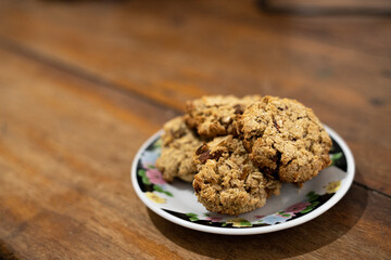 cookies, oatmeal cookies resting over a little dish plate, on a wooden table