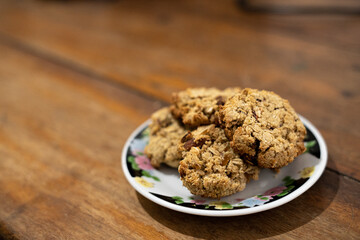 cookies, oatmeal cookies resting over a little dish plate, on a wooden table