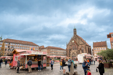 Nuremberg, Germany, August 1, 2023. The magnificent market square on a rainy day. People pass by the fruit and vegetable and street food stalls. Passage of dark clouds in the sky.