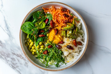 Vegetarian bowl with orange, avocado, salad, fennel, carrots, edamame, rocket and roasted almonds...