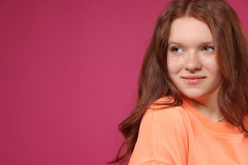 Fototapeta premium Beautiful teenage girl with freckles on pink background, space for text