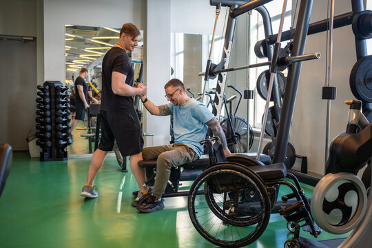 Compassionate trainer supports disables athlete in navigating wheelchair transition post training. Sports safety and confidence, coach ensures smooth transfer, inclusive exercise, post injury training