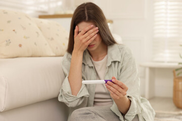 Upset woman with negative pregnancy test at home