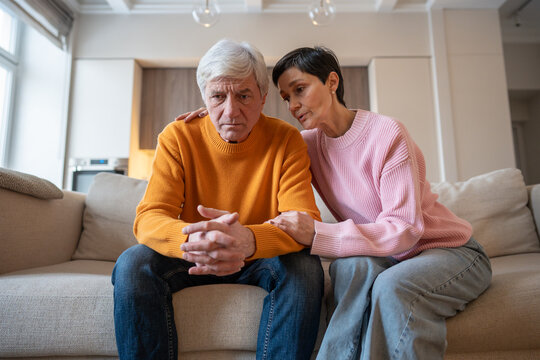 Caring sad wife provides emotional support to depressed husband on couch during tough times. Financial family struggles, work problems, marital support, relationship challenges, comforting spouse