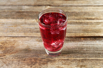 Sweet soda water with ice cubes in glass on wooden table, closeup