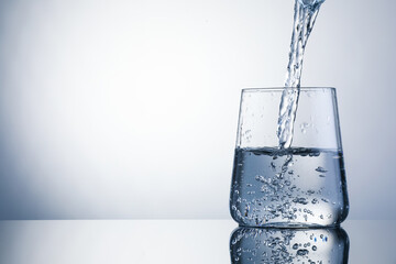 Pouring refreshing soda water into glass on light grey background, closeup. Space for text