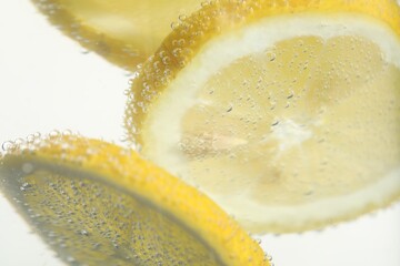 Soda water with lemon slices as background, closeup