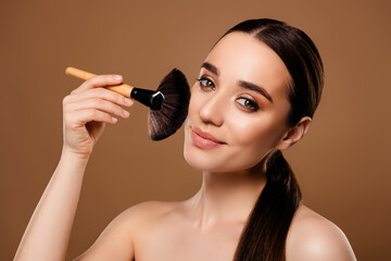 Photo of lovely lady applying decorative cosmetics contouring face isolated on beige color...