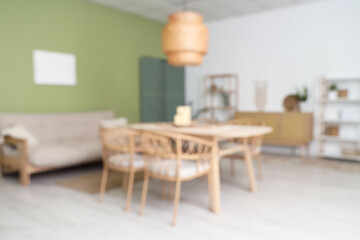 Interior of modern living room with comfortable sofa and dining table. Blurred view