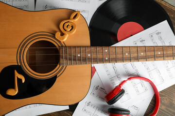 Guitar, music sheets, headphones and vinyl disk on wooden table, closeup