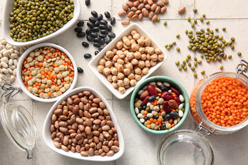 Composition with different raw legumes on light tile background