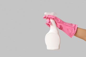 Female hand with mold remover on grey background