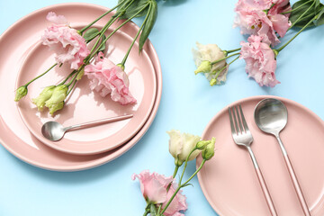 Stylish table setting with beautiful eustoma flowers on blue background