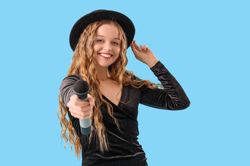 Beautiful young woman with microphone on blue background