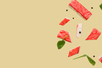 Cut tasty crab sticks with peppercorns and spinach leaves flying on green background © Pixel-Shot