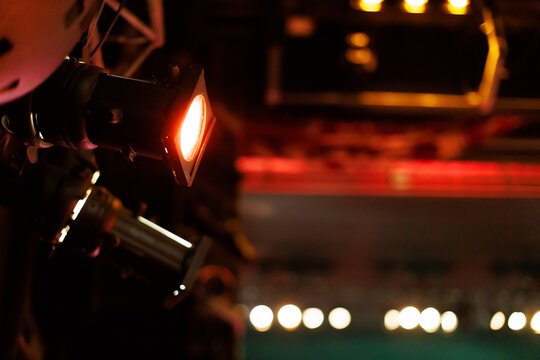 Lighting equipment illuminates a performance stage during an evening event in a vibrant theater setting