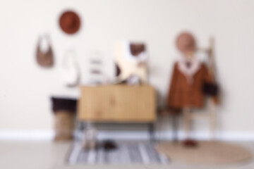 Chest of drawers, ladder with jacket, decor and accessories in interior of hallway. Blurred view