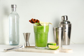 Marble cutting board, glass of bloody Mary cocktail garnished with bacon, lime and celery on white...