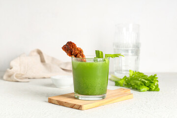 Wooden tray, glass of bloody Mary cocktail garnished with bacon and celery on white background