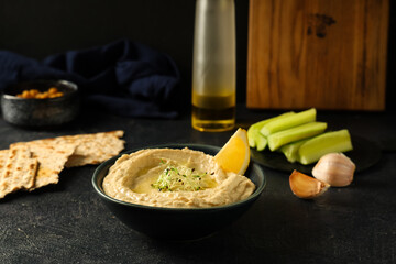 Bowl of delicious hummus with lemon and micro green on grunge background