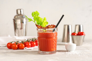 Glass of bloody mary cocktail with bacon and celery on grey table