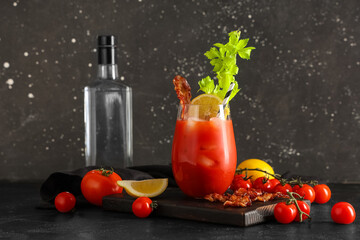 Glass of bloody mary cocktail with bacon, celery and lemon on black background